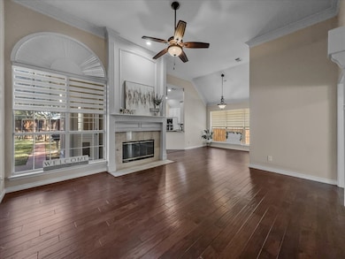 Unfurnished living room featuring ornamental molding, ceiling fan, vaulted ceiling, a tile fireplace, and dark wood-style floors