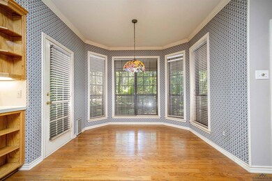 Unfurnished dining area featuring crown molding, wallpapered walls, light wood-style floors, and baseboards