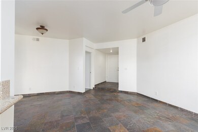 Spare room with dark stone finish flooring and a ceiling fan