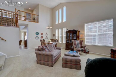 Carpeted living room with a chandelier, baseboards, stairs, a high ceiling, and recessed lighting