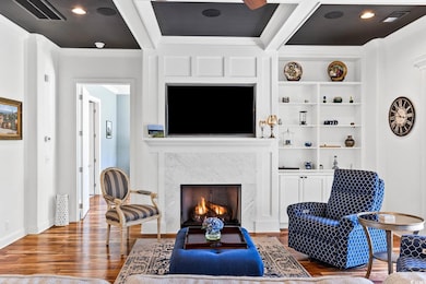 Living area featuring crown molding, wood finished floors, a fireplace, and built in features