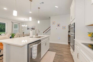 Kitchen featuring appliances with stainless steel finishes, light wood-style floors, a kitchen breakfast bar, a center island with sink, and white cabinetry