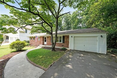 View of front facade featuring brick siding, asphalt driveway, a garage, and a front yard