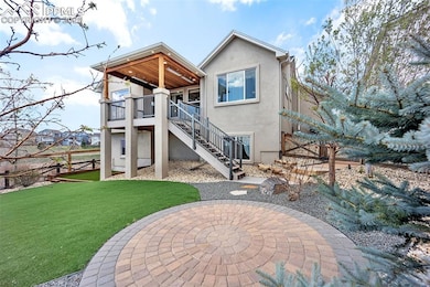 Back of house featuring stucco siding, stairway, a yard, and a patio
