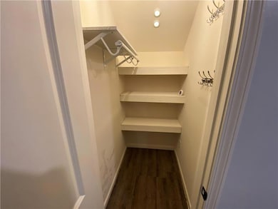 Walk in closet with dark wood-style flooring