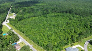 Aerial view of property and surrounding area featuring a forest