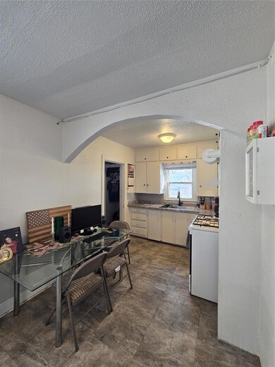 Kitchen featuring arched walkways, white cabinets, stove, a textured ceiling, and an office area