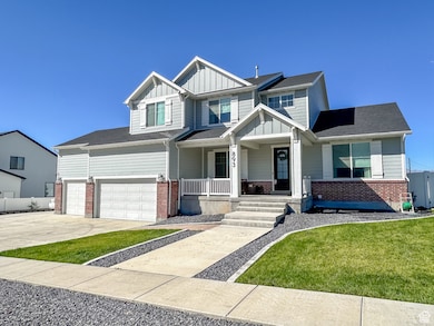 Craftsman-style house with board and batten siding, covered porch, driveway, brick siding, and an attached garage