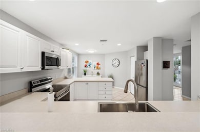 Kitchen featuring appliances with stainless steel finishes, white cabinetry, sink, and light tile patterned flooring