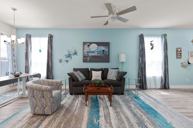 Living area featuring wood finished floors, ceiling fan, and a chandelier