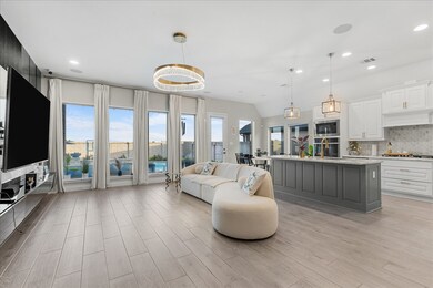 Abundant natural light, elegant light fixtures, and expansive windows offering views of a pool area