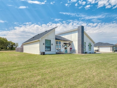 View of front of home with board and batten siding, brick siding, a front lawn, and roof with shingles