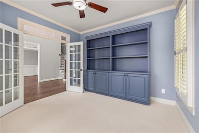 Unfurnished room featuring carpet flooring, french doors, ornamental molding, and ceiling fan