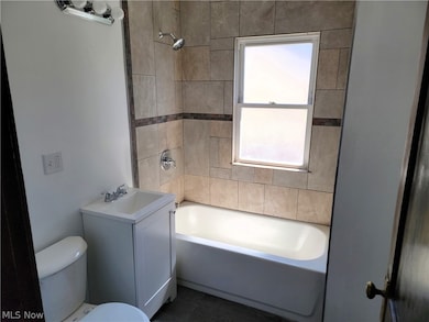 Full bathroom featuring tiled shower / bath combo, sink, tile floors, and toilet