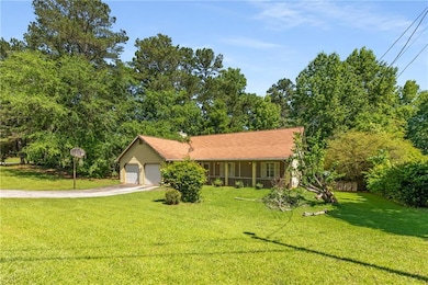 Ranch-style home with driveway, a front lawn, a garage, and covered porch