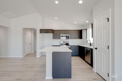 Kitchen with a kitchen island, lofted ceiling, stainless steel appliances, light wood-type flooring, and recessed lighting