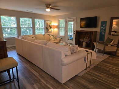 Living area with ceiling fan, dark wood-style flooring, healthy amount of natural light, and baseboards