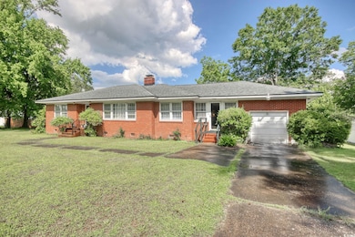Ranch-style home featuring an attached garage, driveway, brick siding, and crawl space