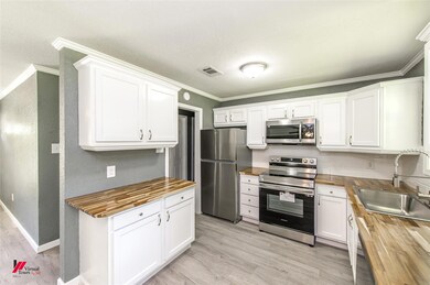 Kitchen with crown molding, wood counters, light h