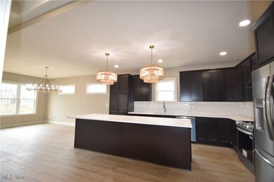 Kitchen with a chandelier, backsplash, decorative light fixtures, stainless steel appliances, and a center island