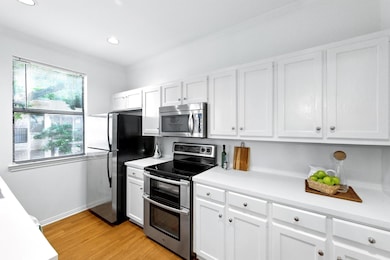 Kitchen with light countertops, white cabinetry, 