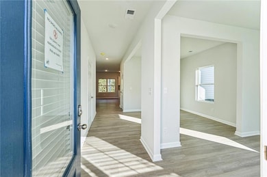 Hall with wood finished floors, baseboards, and recessed lighting