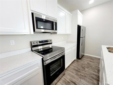 Kitchen featuring appliances with stainless steel finishes, white cabinetry, wood finished floors, light stone counters, and recessed lighting