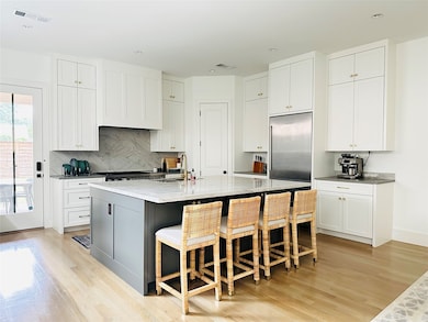 Kitchen with light wood-type flooring, a kitchen bar, gray cabinetry, white cabinets, and recessed lighting