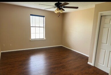 Empty room with a textured ceiling, dark wood finished floors, and ceiling fan