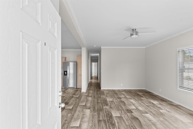 Unfurnished living room with light wood-style flooring, ornamental molding, and ceiling fan