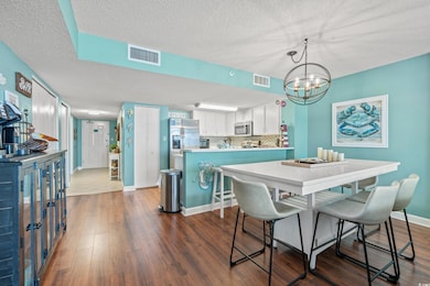 Dining room with a notable chandelier, dark hardwood / wood-style floors, and a textured ceiling