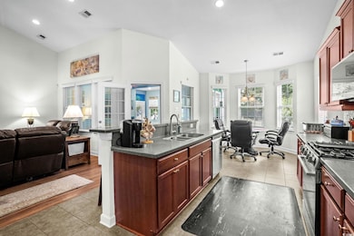 Kitchen featuring light tile patterned floors, open floor plan, black range with gas stovetop, healthy amount of natural light, and recessed lighting