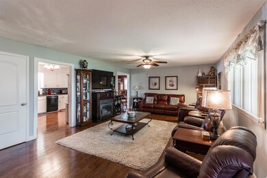 Large living room with lots of natural light with new ceiling fan and wood flooring. 