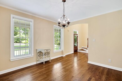 Dining room featuring healthy amount of natural light, ornamental molding, a chandelier, wood finished floors, and arched walkways