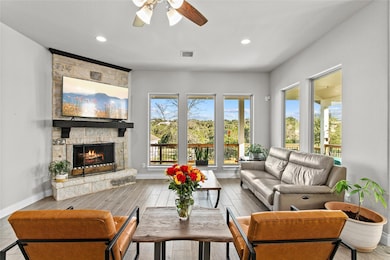 Living area with a fireplace, ceiling fan, basebo