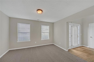 Carpeted empty room with baseboards and visible ve