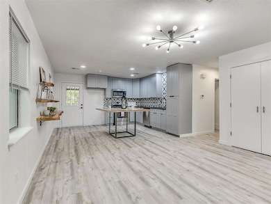 Kitchen with gray cabinetry, tasteful backsplash, light wood-style flooring, appliances with stainless steel finishes, and butcher block countertops