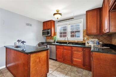 Kitchen featuring dark stone countertops, tasteful backsplash, appliances with stainless steel finishes, and sink