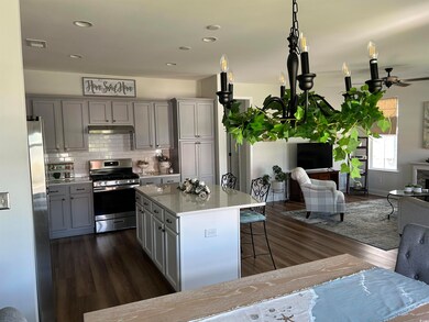 Full Kitchen featuring a breakfast bar, stainless steel appliances, solid surface counter tops and under cabinet range hood, gray cabinetry.