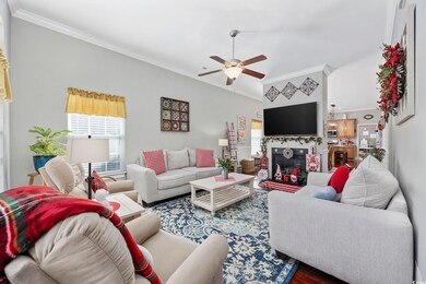 Living room with crown molding, ceiling fan, and h
