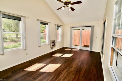 Wood floored empty room featuring vaulted ceiling 