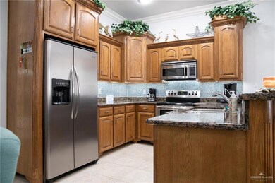 Kitchen featuring stainless steel appliances, crown molding, sink, and dark stone countertops
