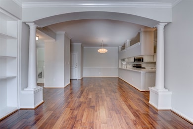 Another angle of the spacious living area, featuring an open layout with classic columns and rich hardwood floors that tie it all together.