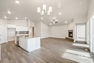 Kitchen with lofted ceiling, dishwasher, white cabinetry, ceiling fan, and a chandelier