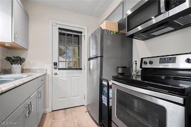 Kitchen featuring gray cabinets, appliances with stainless steel finishes, and light wood finished floors