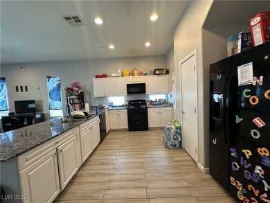 Kitchen with black appliances, white cabinets, a p