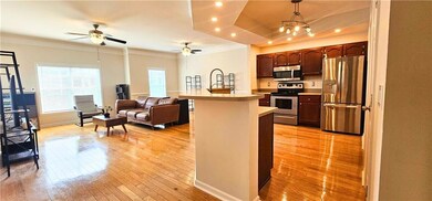 Kitchen with stainless steel appliances, light wood finished floors, ornamental molding, open floor plan, and a ceiling fan