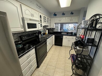 Kitchen with white cabinets, black appliances, sin