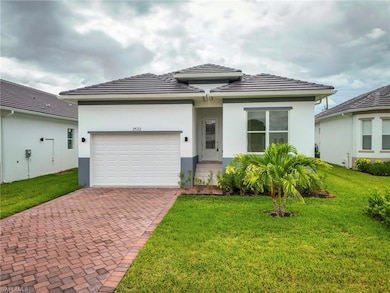 Prairie-style home featuring an attached garage, decorative driveway, stucco siding, a front lawn, and a tile roof