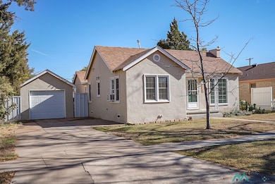 View of front of home featuring driveway, an outbuilding, a garage, stucco siding, and a shingled roof